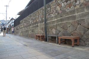 别府Beppu Kannawa Onsen HIROMIYA的石墙旁人行道上的两把长椅