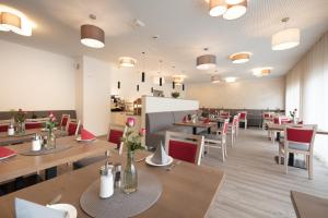 里德林根Hotel Gudrun的餐厅设有木桌和红色椅子