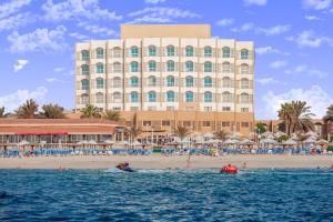 沙迦沙迦卡尔顿酒店的海滩上一座大型建筑,在水中划船