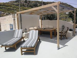 安坡里奥圣托里尼Katsinaros House的屋顶上带木桌和椅子的庭院