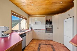 皇后镇Amazing View Home的厨房配有白色橱柜和木制天花板