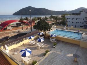 伯迪亚哥27 Praia Hotel - Frente Mar的海滩旁带桌子和遮阳伞的游泳池