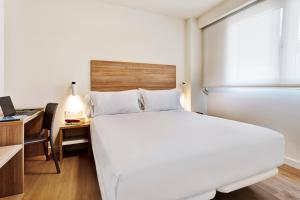 洛格罗尼奥Sercotel Logroño Suites的卧室配有一张白色大床和一张书桌