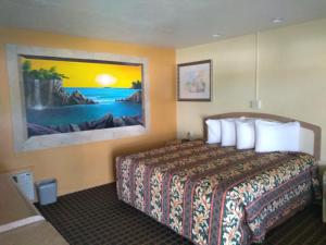 代托纳海滩代托纳海滩超级旅馆的酒店客房设有一张床,墙上挂有绘画作品