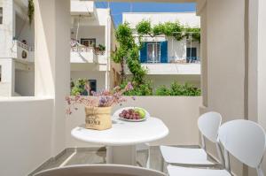 纳克索乔拉Villa Agape的阳台上的白色桌椅,上面放着一碗水果