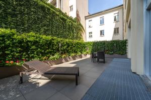 米兰米兰城堡酒店的庭院设有2个长椅和绿色树 ⁇ 