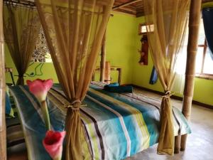 El AchioteHotel Rio Celeste Finca L´ Etoile Celeste的一间卧室配有带窗帘和鲜花的床