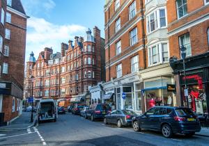 伦敦肯辛顿高街公寓的一条繁忙的城市街道上,街上有汽车停放