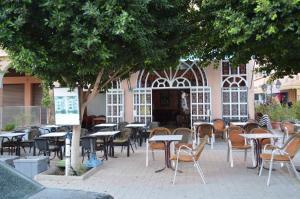 瓦尔扎扎特Hotel Atlas Ouarzazate的树下带桌椅的空庭院
