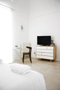 特拉尼La Mitria的一间白色卧室,配有电视和椅子
