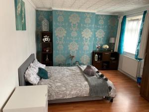 伦敦London budget Maisonette的一间卧室配有床和蓝色壁纸