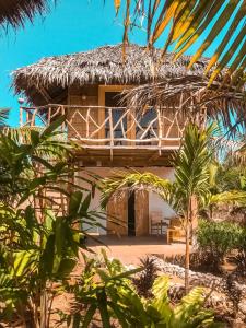 锡基霍尔Mandala Tribe Treehouses的一座带茅草屋顶和棕榈树的度假建筑