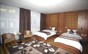 乌兰巴托普玛帝国酒店的一间卧室配有两张床和一张桌子及椅子
