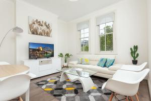 悉尼STUNNING SYDNEY HOME 10的白色的客厅配有白色的沙发和桌子