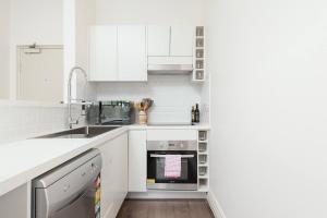 悉尼STUNNING SYDNEY HOME 11的白色的厨房配有白色橱柜和水槽