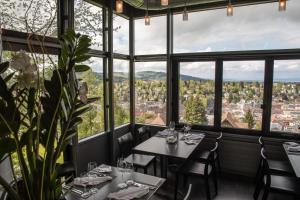 圣加仑Hotel Restaurant Falkenburg的餐厅设有桌椅和大窗户。