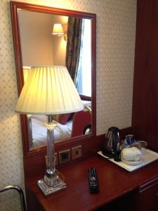 伦敦埃文酒店的一张桌子上的灯,放在带镜子的酒店房间