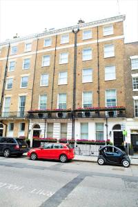 伦敦夏季酒店的停在大型砖楼前的红色汽车