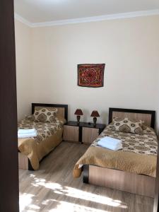撒马尔罕Saroy Guest house的卧室配有两张床,墙上挂着一幅画