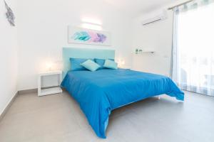 圣特雷莎加卢拉B&B Naracheddu Elite的白色卧室设有蓝色的床和窗户