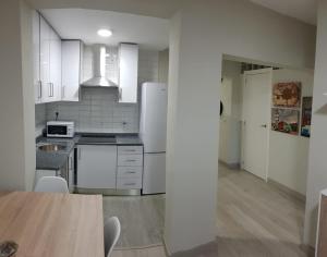 马德里Apartamento Barajas. Aeropuerto/Ifema的厨房配有白色家电和木桌