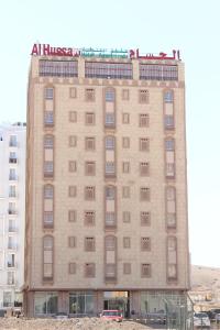 马斯喀特Al Hussam Hotel Apartments的公寓大楼的顶部有标志