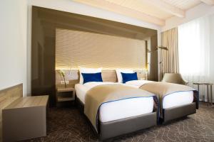 莱比锡Hotel Atlas Leipzig的两张位于酒店客房的床,配有蓝色枕头