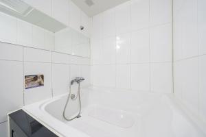 坡州市Q酒店的浴室设有带淋浴的白色浴缸。