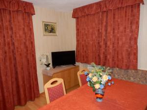 科尔福索La Pineta的配有红色窗帘的桌子和电视的房间