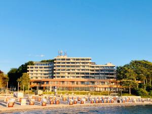 格吕克斯堡Intermar Hotel & Apartments的海滩上一座大型建筑,前面设有椅子