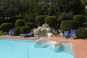 莫内利亚Hotel La Vigna的一个带蓝色椅子和岩石墙的游泳池