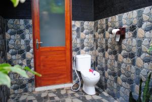 佩母德兰巴厘岛佩母德兰皇冠住宿加早餐旅馆的一间带卫生间和木门的浴室