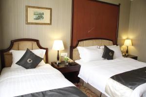 广州科尔海悦酒店的酒店客房设有两张床和两盏灯。