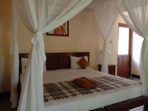 佩母德兰巴厘岛壁虎民宿酒店的卧室配有白色窗帘的床