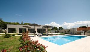 塞尔察Villa Pietra的后院带遮阳伞的游泳池