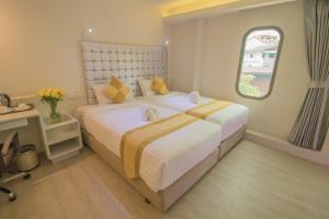 曼谷Justice Hotel的一间卧室设有两张床和窗户。