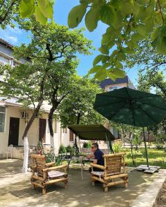 巴统Batumi Summer Hotel的坐在一把伞下椅子上的男人
