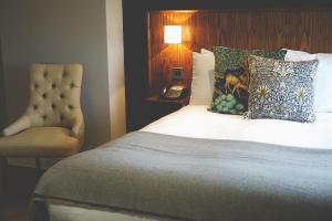 康达格林穆勒康德格林酒店的一间卧室配有一张带椅子和一盏灯的床