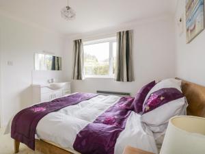 Gorran HavenBrambles的一间卧室配有一张带紫色毯子的床