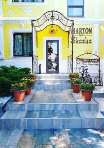 顿河畔罗斯托夫Marton Skazka Hotel的黄色的建筑,有楼梯,花在盆里