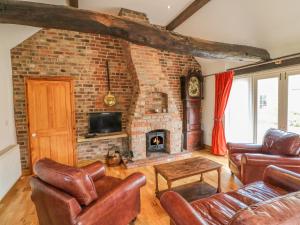 根斯堡Forge Cottage的客厅配有皮革家具和砖砌壁炉