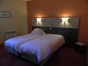 蒙代列赫Hotel Restaurant La Martiniere的卧室配有一张带两个灯的大白色床