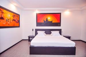 贝岛Hotel La Bombonera的卧室配有一张白色床,墙上挂有绘画作品