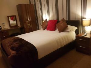 海斯廷斯森拉克旅馆的一间卧室配有一张带红色枕头的大床
