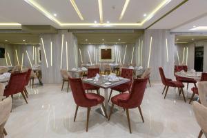 CheragaMADAURE HOTEL的用餐室配有桌子和红色椅子