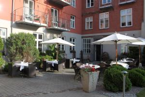 施特拉尔松德豪斯沃弗卡纳酒店的大楼前的户外庭院配有桌子和遮阳伞