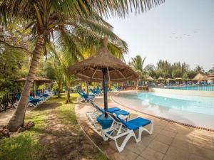 Sere Kunda NDingSenegambia Beach Hotel的一组椅子和遮阳伞,位于游泳池旁