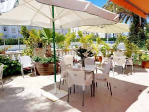 比利亚霍约萨El Artista的庭院配有白色的桌椅和遮阳伞。