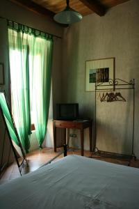 托尔基亚拉罗萨卡尼雅住宿加早餐旅馆的一间卧室配有一张床、一张书桌和绿色窗帘