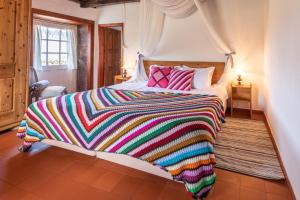 Faja GrandeAldeia da Cuada的一张大床,上面有五颜六色的毯子